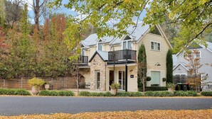 A two-story house with a stone facade, a balcony, and a garage. - Beyond Bliss - Guesthouse 1 (BRIGHT)