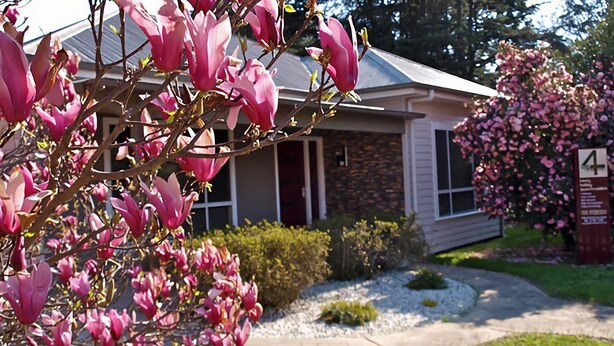 Une maison avec une façade en pierre, une porte d’entrée et une allée menant à un garage.