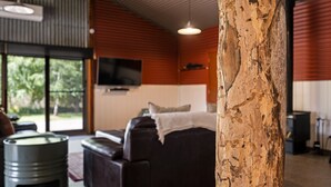 A cozy room with a large window, a sofa, a TV, and a wooden pillar. - Quins Gap Escapes (Bright)