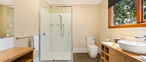 Een moderne badkamer met een douchecabine van glas, een toilet, een wastafel en een houten opbergmeubel.