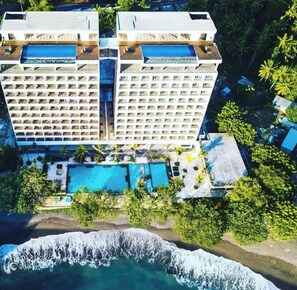 Un hôtel de grande hauteur doté de nombreux balcons, d’un espace piscine et offrant une vue sur la plage.