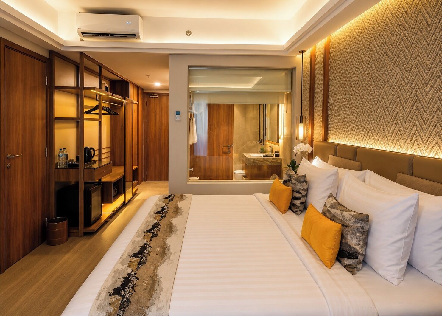 Habitación de hotel con una cama grande, vestidor, baño con espejo y pared con diseño.
