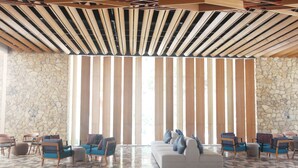 Un hall espacioso con un diseño moderno, que incluye un sofá grande, varias sillas y un suelo con estampado.