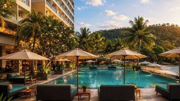 A hotel pool area with lounge chairs and umbrellas, surrounded by palm trees and a building.