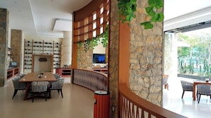 A modern interior with a dining area, a kitchen, and a stone wall with greenery. - Louis Kienne Resort Senggigi (Senggigi)