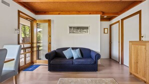 A cozy living room with a blue sofa, wooden beams on the ceiling, and a framed picture on the wall. - Kalamunda 6 - On the Rail Trail (BRIGHT)