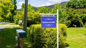 A sign for 'Kalamunda' in a lush, green setting with a mailbox and a telephone pole. - Kalamunda 6 - On the Rail Trail (BRIGHT)