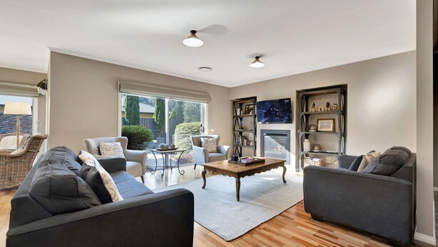 A spacious living room with a fireplace, two sofas, a coffee table, and a bookshelf.