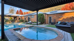 A backyard with a swimming pool, a hot tub, and outdoor seating.