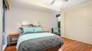 Ein Schlafzimmer mit Bett, Nachttischen, einem Kleiderschrank und einem Fenster.