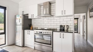 A modern kitchen with white cabinetry, a stainless steel range, and a built-in oven. - 2 Minutes By Bike - On the Rail Trail (BRIGHT)