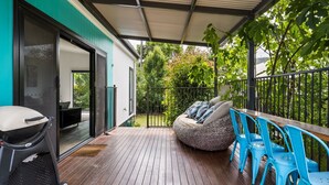 A covered outdoor area with a wooden deck, a seating area with cushions, and a grill. - 2 Minutes By Bike - On the Rail Trail (BRIGHT)