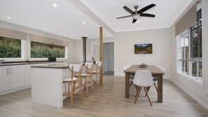 Una cocina moderna con armarios blancos, una mesa de comedor de madera y un ventilador de techo.