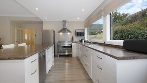 Cocina moderna con armarios blancos, electrodomésticos de acero inoxidable y un amplio ventanal con vistas al exterior.
