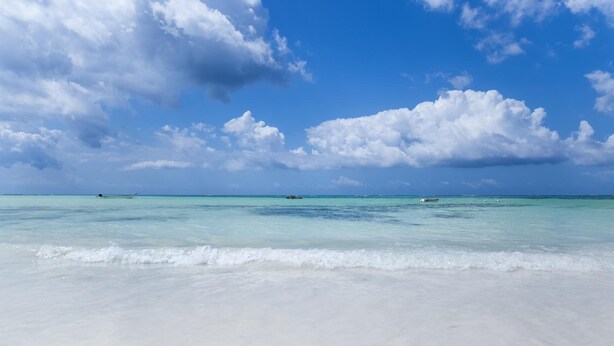 Na praia, areia branca, espreguiçadeiras 