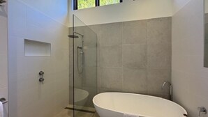 Une salle de bain moderne dotée d’une douche à parois de verre, d’une baignoire sur pied et d’un design minimaliste.