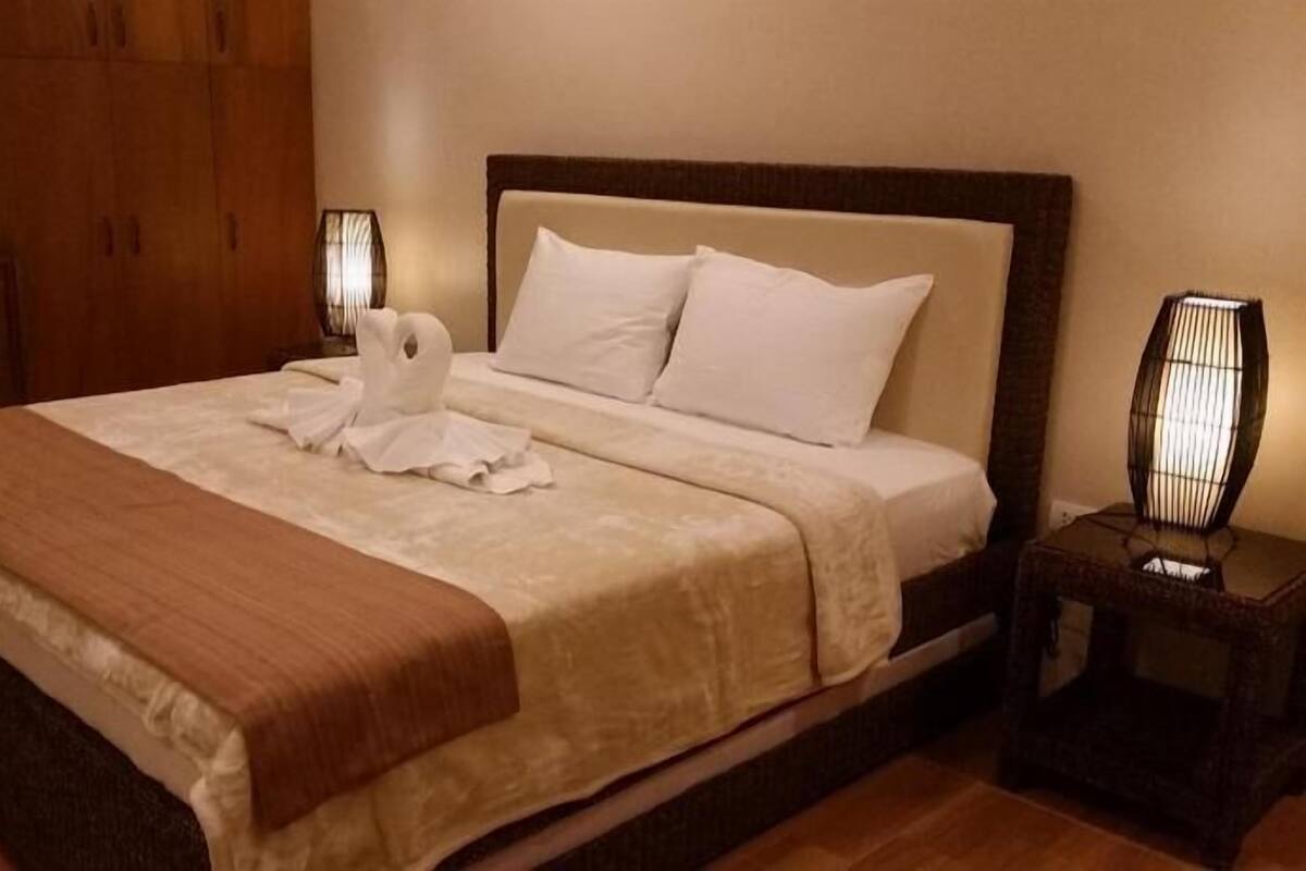 A hotel room with a bed, a desk, and a nightstand.