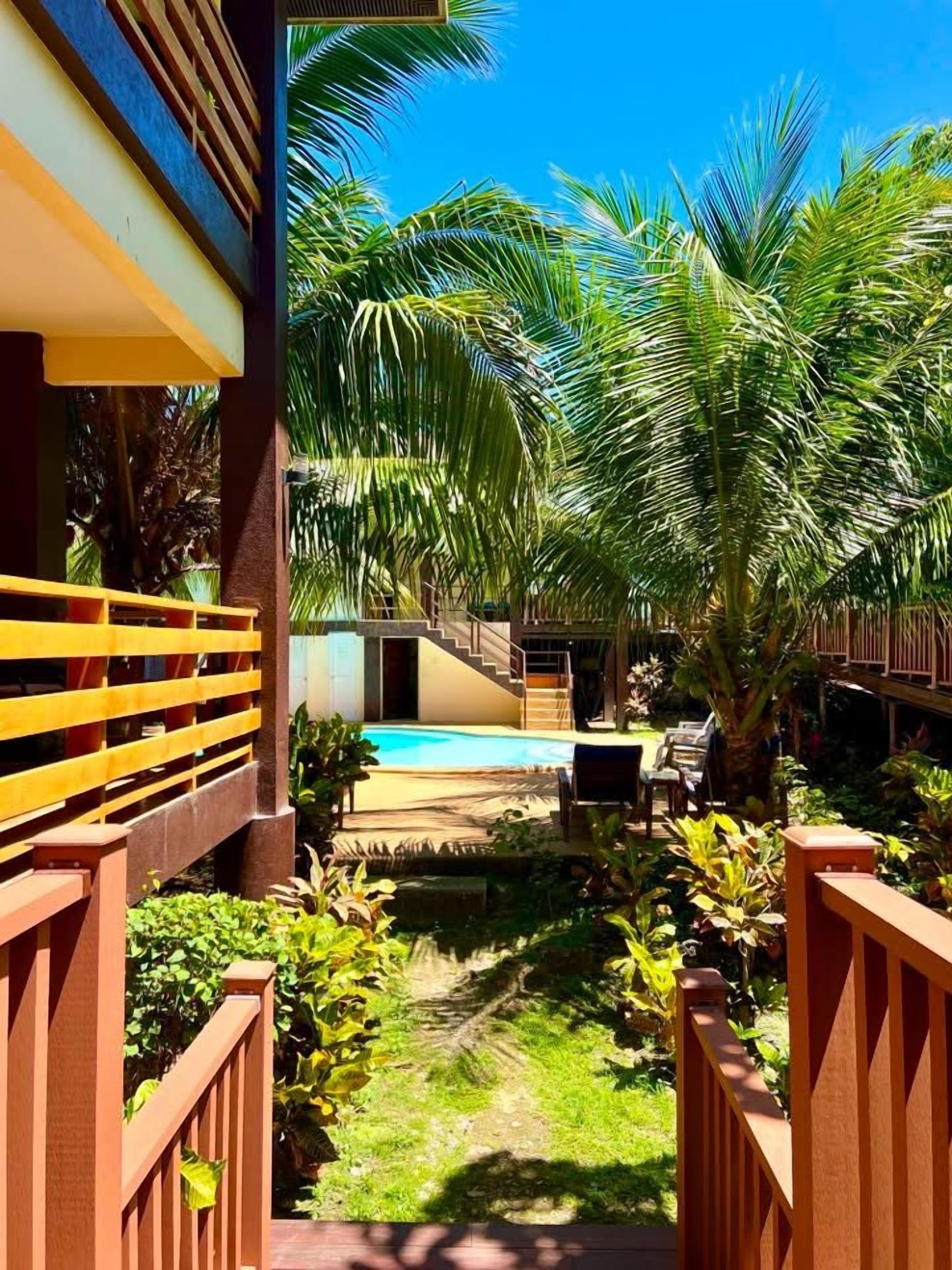 A pool area with a clear view of the pool, surrounded by lush greenery and a wooden deck.