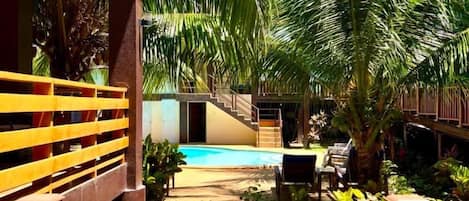 A pool area with a clear view of the pool, surrounded by lush greenery and a wooden deck.