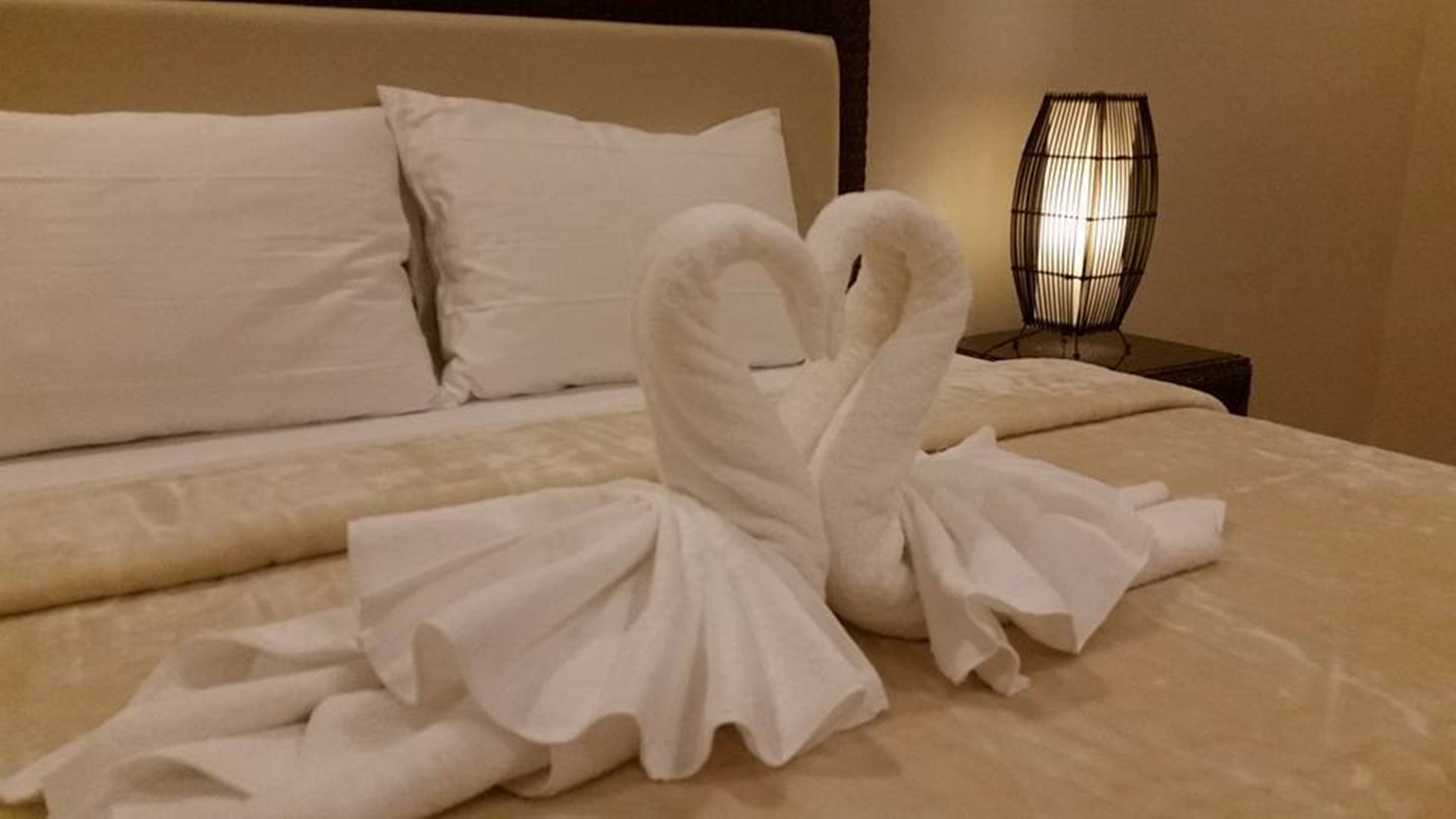A neatly made bed with a swan-shaped towel arrangement.