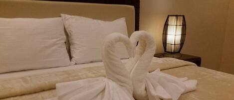 A neatly made bed with a swan-shaped towel arrangement.