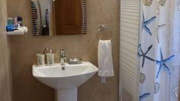A bathroom with a pedestal sink, a mirror, a towel rack, and a shower curtain with starfish designs.