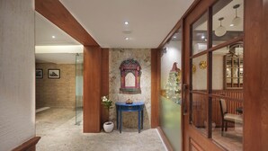 A hallway with a wooden door, a decorative archway, and a small table with a potted plant. - Vaydantaa - Luxury Boutique Hotel Mussoorie (Dehradun)