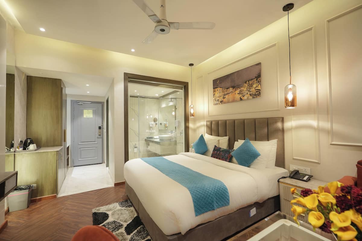 A hotel room with a large bed, a desk, a chair, a bathroom, and a ceiling fan.
