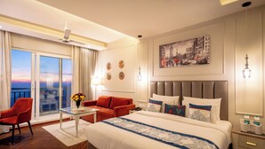 A hotel room with a large bed, a sofa, a table, and a balcony with a view. - Vaydantaa - Luxury Boutique Hotel Mussoorie (Dehradun)