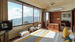 A hotel room with a bed, a TV, a desk, a chair, and a view of the mountains. - Vaydantaa - Luxury Boutique Hotel Mussoorie (Dehradun)