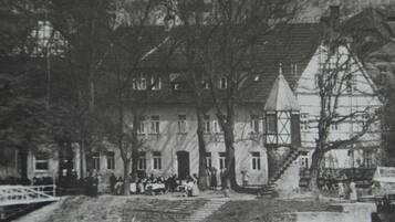 A historic building with a prominent tower, a staircase leading to the entrance, and a river in the foreground.