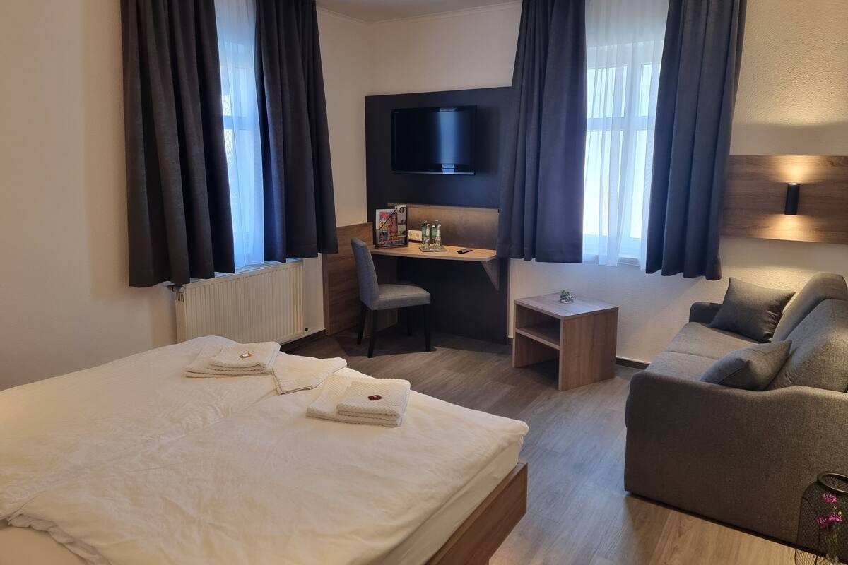 Een hotelkamer met een groot bed, een bureau, een stoel, een bank en een televisie.