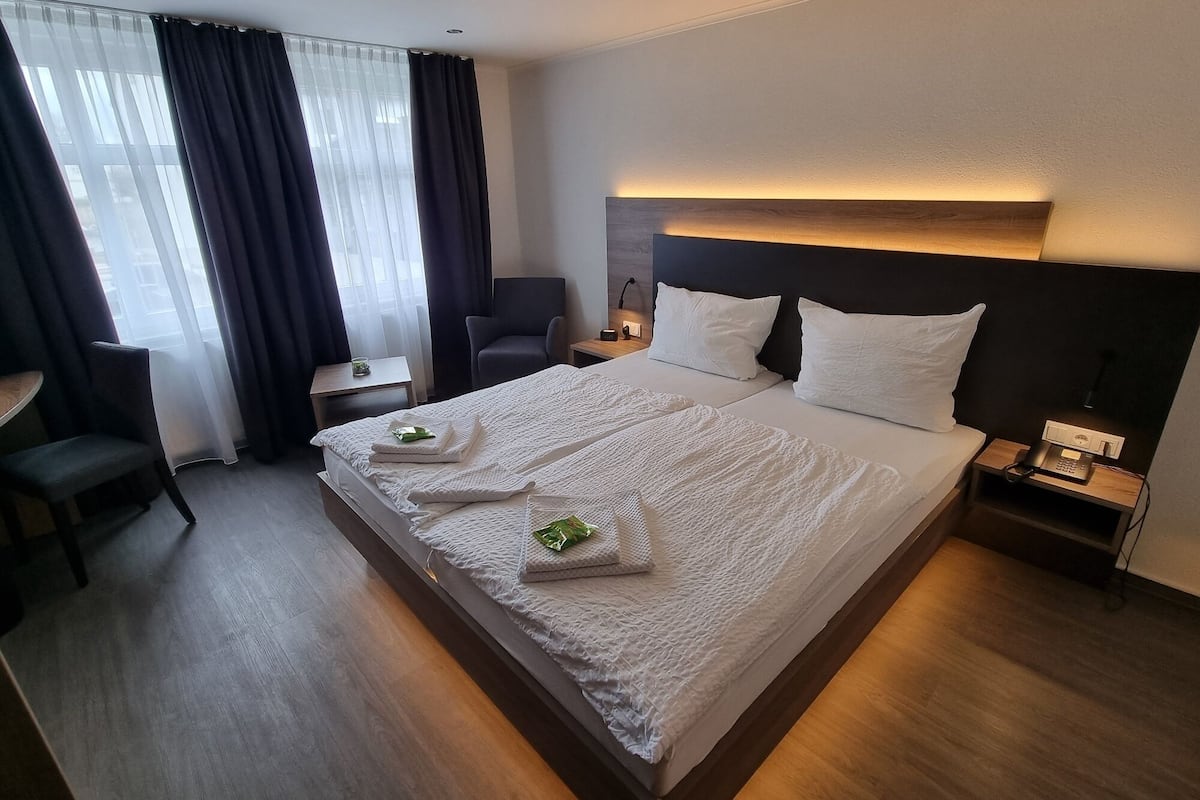 Een hotelkamer met een groot bed, een bureau, een stoel en een nachtkastje met een telefoon.