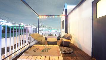 A balcony with wicker furniture, a table with a placemat, and string lights.