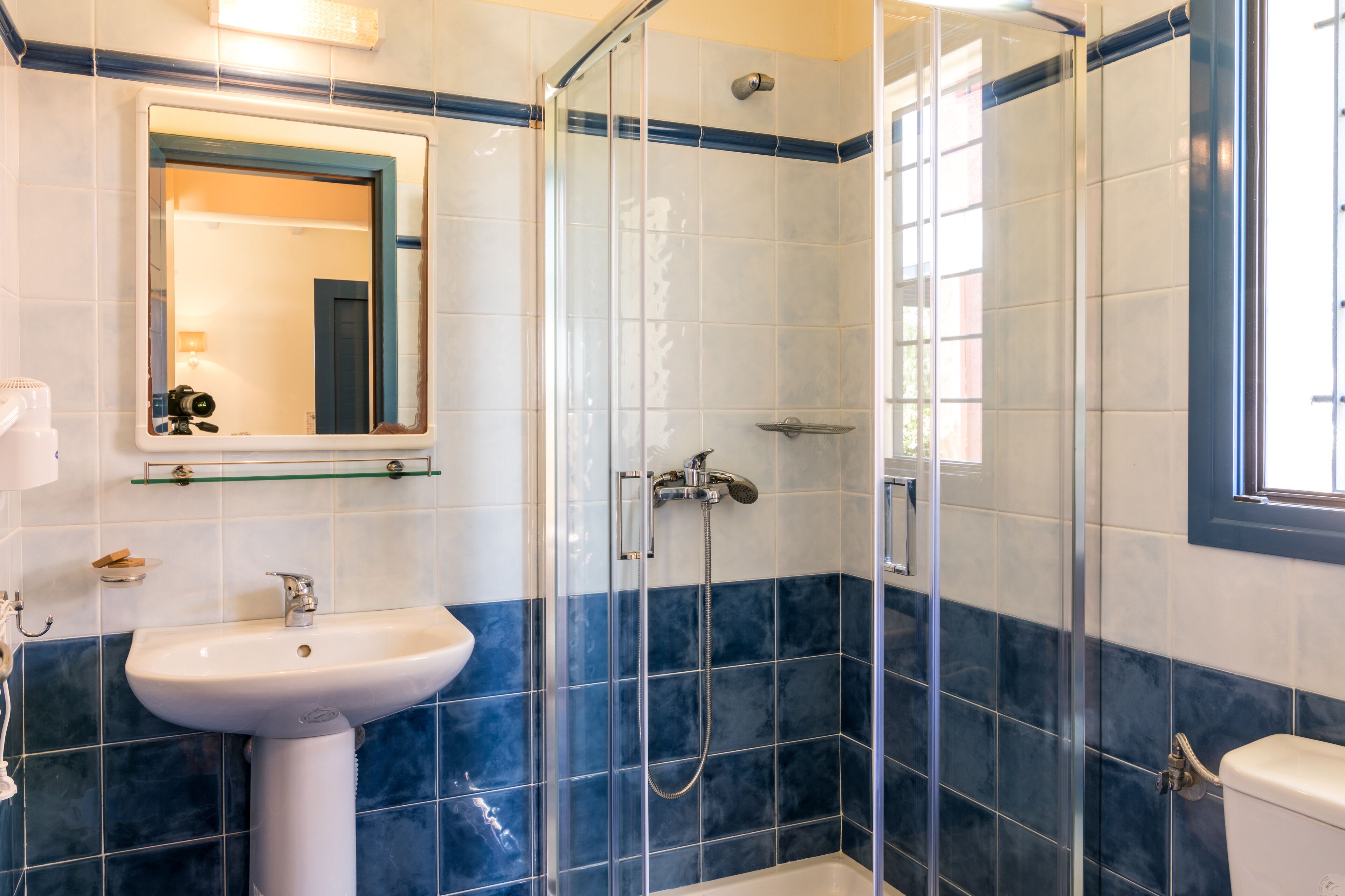A bathroom with a glass-enclosed shower, a sink, and a toilet.