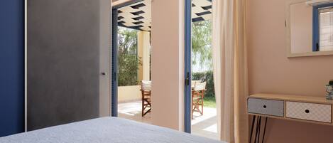 Un dormitorio con cama, escritorio con cajones y vista a un patio exterior.