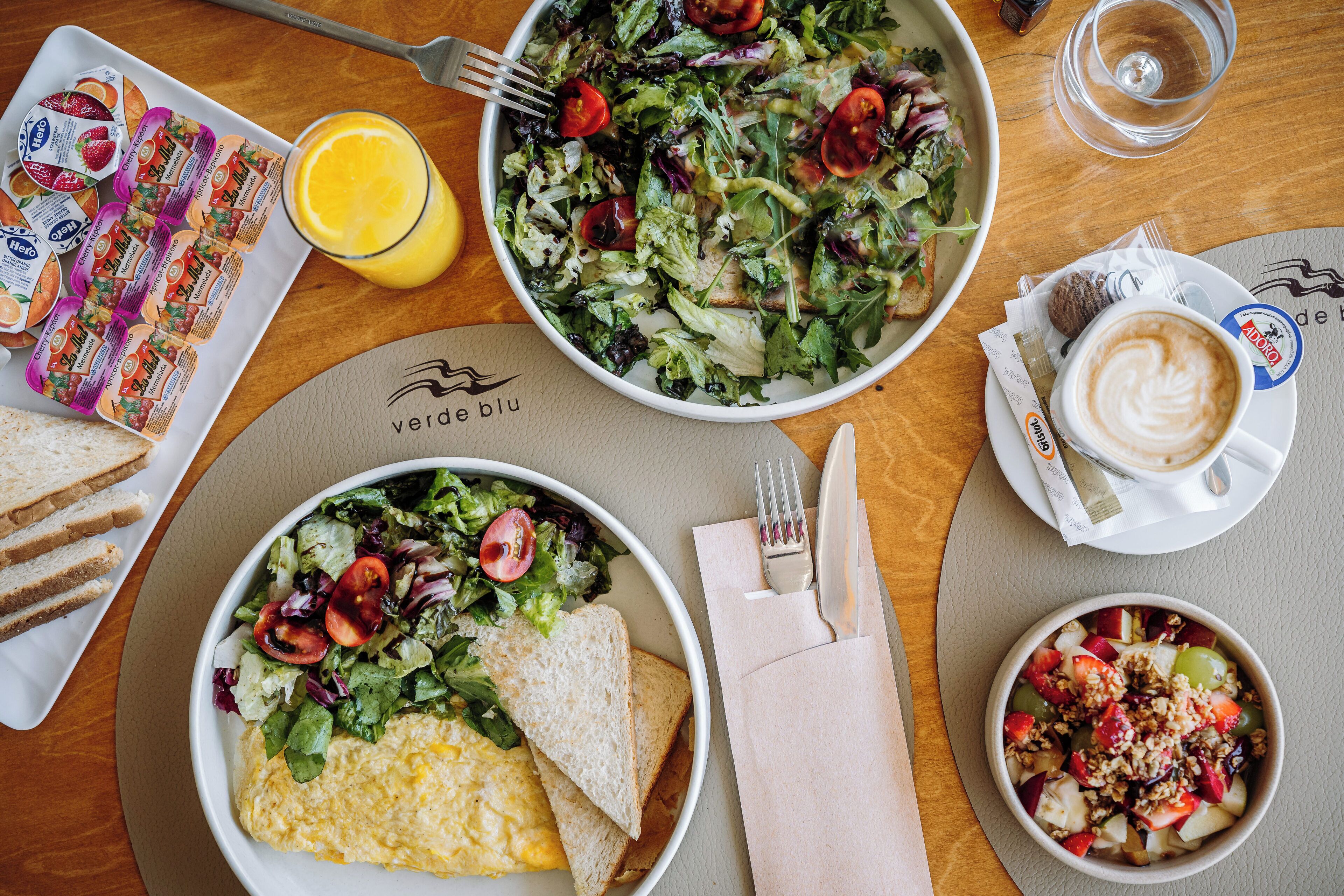 A breakfast setting with a salad, omelette, toast, and coffee on a wooden table.