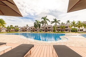 Una piscina al aire libre, sombrillas, sillones reclinables de piscina
