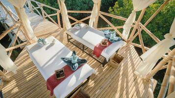 Relax in a serene outdoor space surrounded by lush greenery, featuring two lounge chairs and small tables.
