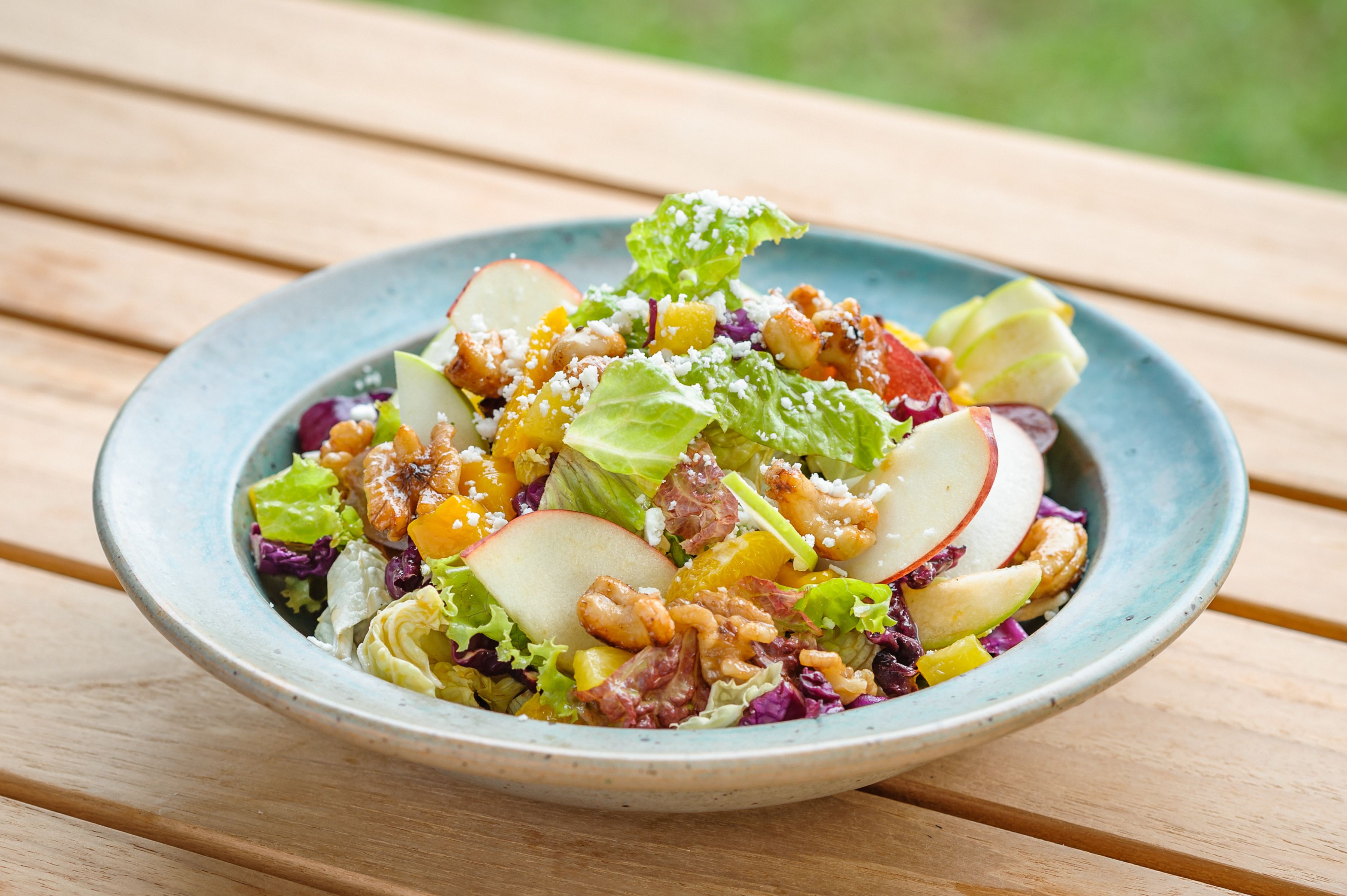 A bowl of salad on a wooden table.