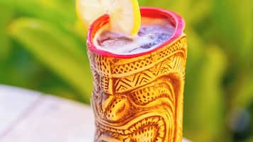 Un vaso tiki con diseño tallado, lleno de una bebida y una rodaja de limón encima.