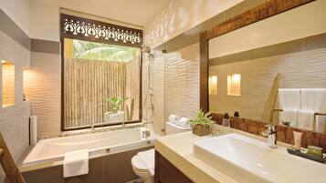 A modern bathroom with a bathtub, toilet, and sink. There is a large mirror, a shower, and a window with bamboo blinds.