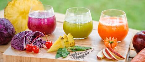 A wooden board with various fruits and vegetables, including a pineapple, red cabbage, cherries, and a carrot.
