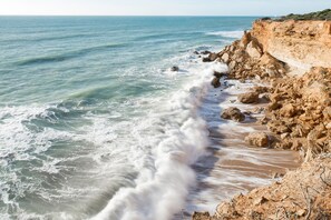 Un paysage côtier avec une rive rocheuse et des vagues qui déferlent sur la plage.