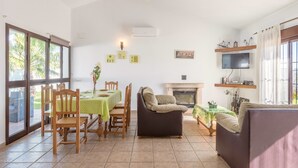 A dining area with a table and chairs, a sofa, a fireplace, and a television.
