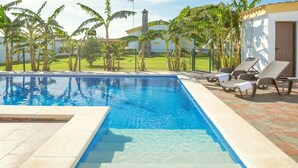 A swimming pool with clear water, surrounded by a tiled deck, and equipped with sun loungers.