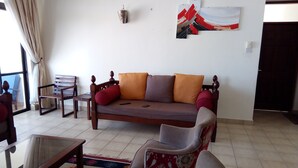 Una sala de estar con un sofá, sillones, una mesita de centro y un tapete estampado.