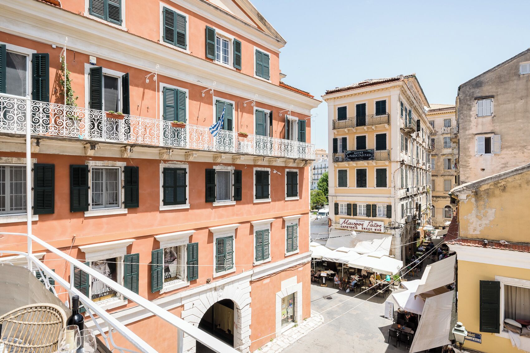 Un immeuble à plusieurs étages doté de balcons, avec un café au rez-de-chaussée et une enseigne bien visible indiquant la présence d’un hôtel.