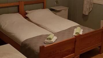 Una cama doble con cabecera y piecera de madera, una mesita de noche y una mesilla con lámpara.