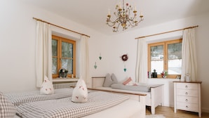 A cozy bedroom with a bed, a dresser, and a window with curtains. - Ferienhaus Heimhof (Garmisch-Partenkirchen)